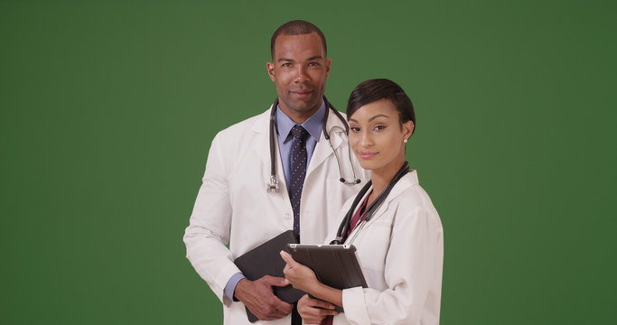 Two African American doctors holding their tablets on green screen - Powered by Adobe