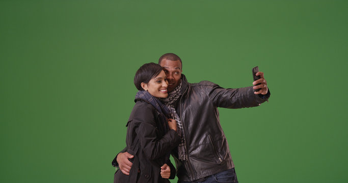 A black couple poses for a picture on green screen