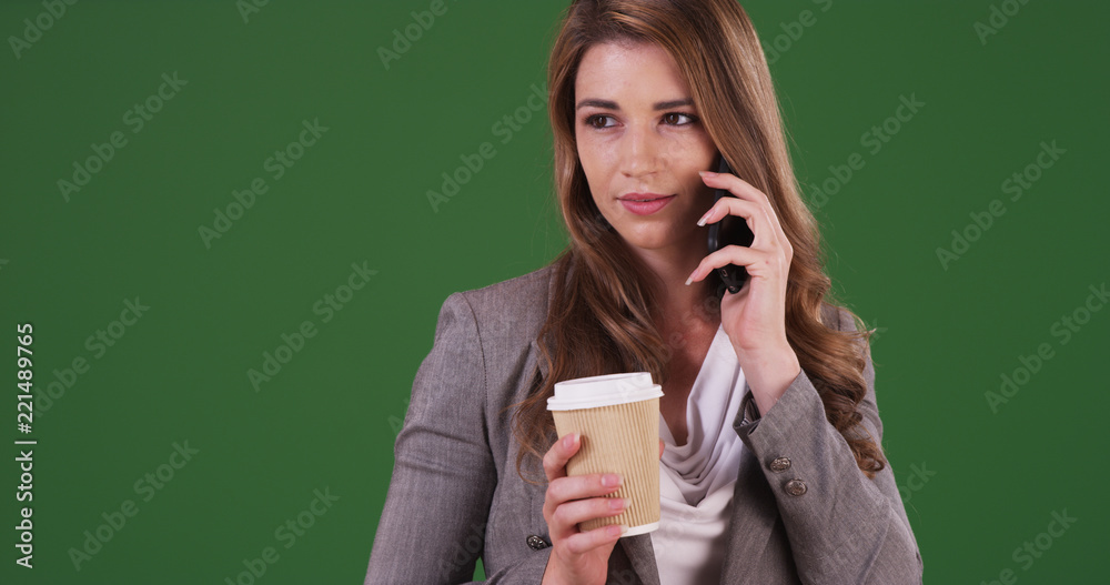 Wall mural Young businesswoman talking on the phone with a client on green screen