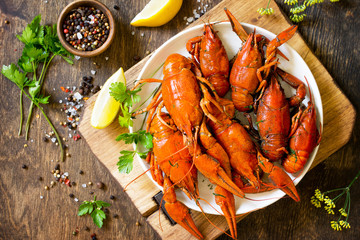 Boiled crawfish, lemon and parsley on a wooden table. Appetizer protein, the concept of healthy eating. Top view flat lay background. Copy space.