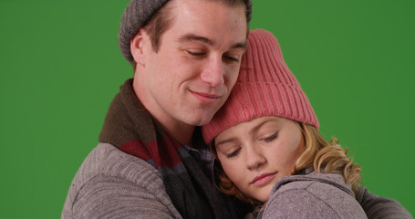 Close up of boyfriend and girlfriend in winter attire embracing on green screen