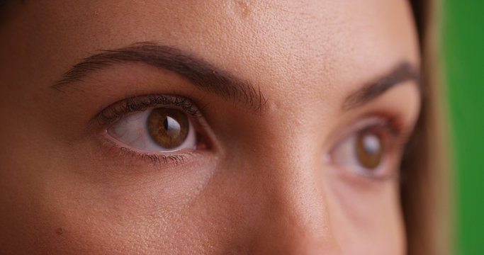 Close view of millennial brunette's eyes looking offscreen on green screen