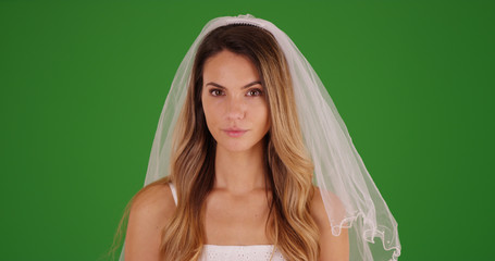 Beautiful female millennial standing in a wedding dress and veil on green screen