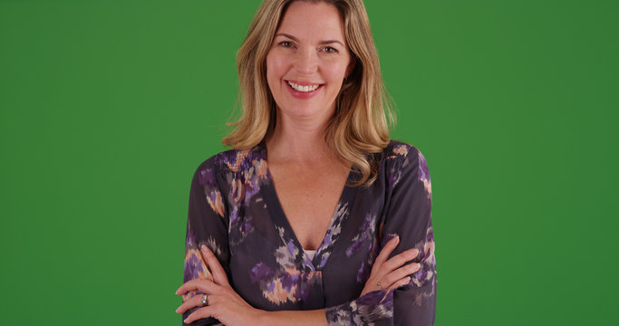Middle aged woman in blouse smiling at camera on green screen