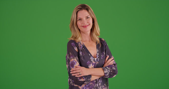 Caucasian woman with arms crossed smiling at camera on green screen