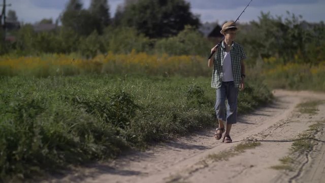 Hillbilly boy goes fishing with a fishing rod in the village