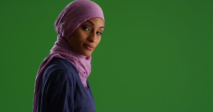 Portrait of black woman wearing hijab looking at camera on green screen