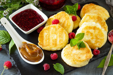 Breakfast background. Homemade cottage cheese pancakes with condensed milk, raspberry jam on slate board.