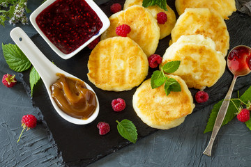 Breakfast background. Homemade cottage cheese pancakes with condensed milk, raspberry jam on slate board.