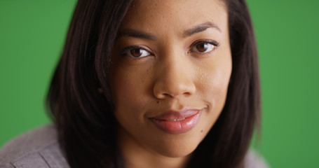 Close up portrait of charming black female smiling at camera on green screen