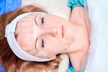 Kinesiotaping. Young woman lying with tape on her face. Physiotherapy and cosmetology procedure. Method of non-surgical skin rejuvenation. Facial skin care