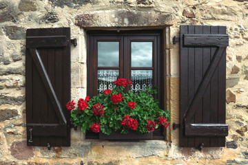 window with wood shutters and red geranium