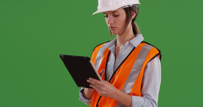 Woman worker in orange vest with tablet computer and hard hat on greenscreen - Powered by Adobe