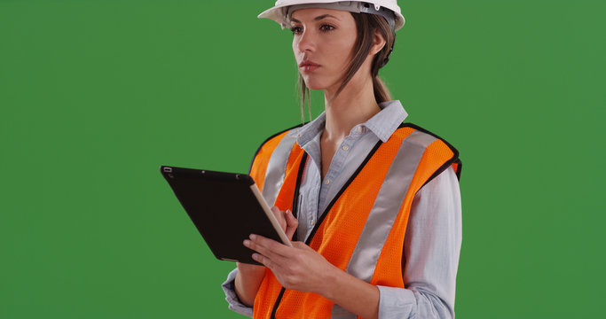 Woman in orange vest with tablet device and hardhat working on green screen - Powered by Adobe