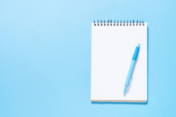 Notebook and pen on blue background.