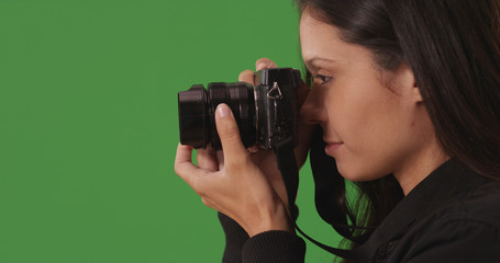 Profile of female photographer using camera to take pictures on green screen