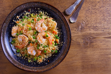 Shrimps with couscous, green peas, leeks and carrot. View from above, top studio shot