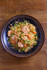 Shrimps with couscous, green peas, leeks and carrot. View from above, top studio shot