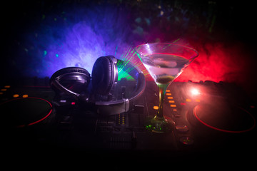 Glass with martini with olive inside on dj controller in night club. Dj Console with club drink at...