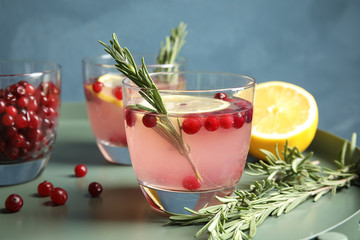 Tasty refreshing cranberry cocktail with rosemary on table