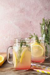 Refreshing lemon cocktail with rosemary in mason jars on table