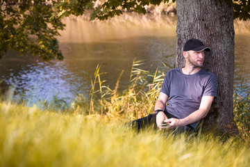 brutal man resting on the grass in an autumn forest in the shade of a tree