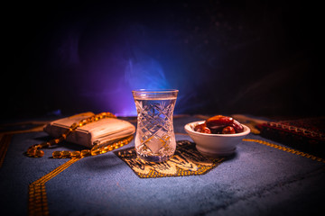 Water and dates. Iftar is the evening meal. View of decoration Ramadan Kareem holiday on carpet. Festive greeting card, invitation for Muslim holy month Ramadan Kareem. Dark background