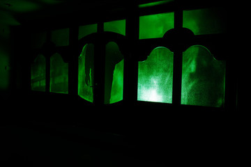 Silhouette of an unknown shadow figure on a door through a closed glass door. The silhouette of a human in front of a window at night. Scary scene halloween concept of blurred silhouette