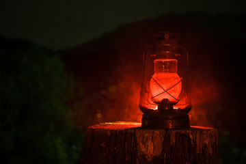 Horror Halloween concept. Burning old oil lamp in forest at night. Night scenery of a nightmare scene.