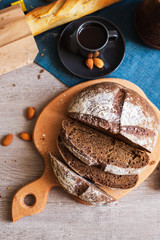 Freshly Baked Homemade Dark Bread with White Flour Sliced on Wooden Board and Cup of Coffee. Close up. Top View.