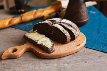 Organic Whole Grain Dark Bread with Fresh Homemade Butter. A Slice of Bread with Butter and Wooden Desk.