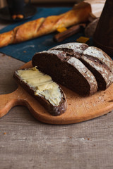 Organic Whole Grain Dark Bread with Fresh Homemade Butter. A Slice of Bread with Butter and Wooden Desk.