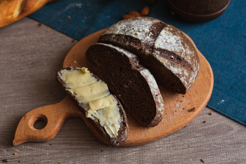 Organic Whole Grain Dark Bread with Fresh Homemade Butter. A Slice of Bread with Butter and Wooden Desk