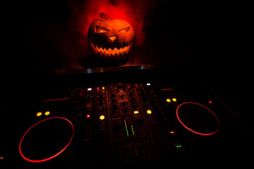 Halloween pumpkin on a dj table with headphones on dark background with copy space. Happy Halloween...