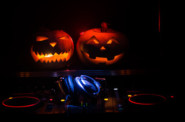 Halloween pumpkin on a dj table with headphones on dark background with copy space. Happy Halloween...