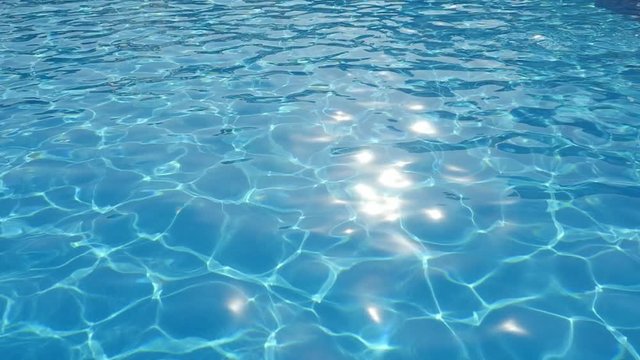 A beautiful view of sky blue waters in a swimming pool shot askew with a glittering network changing its shape in slow motion