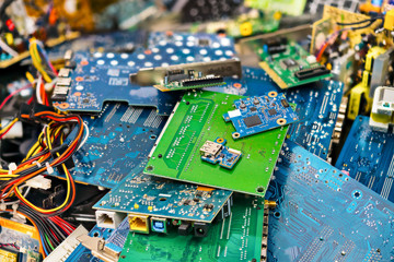 E-waste heap from discarded laptop parts. Connectors, PCB, notebook cards. Colorful blurry background from PC components. Idea of electronics industry, eco, sorting and disposal of electronic waste.