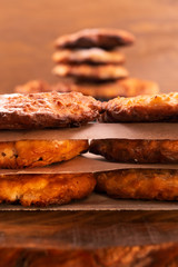Round browned cookies stacked in rows on top of each other, wooden background.