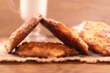 Round cottage cheese cookies with a ruddy crust on a linen napkin, wooden background, close-up.