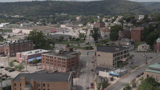 A summer slow reverse high angle aerial establishing shot of the main street in a small town in western Pennsylvania. Pittsburgh suburbs.  	