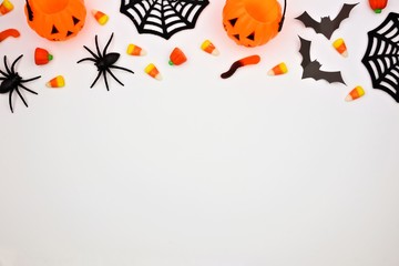 Obraz na płótnie Canvas Halloween top border of scattered candy and decor. Flat lay over a white background. Copy space.