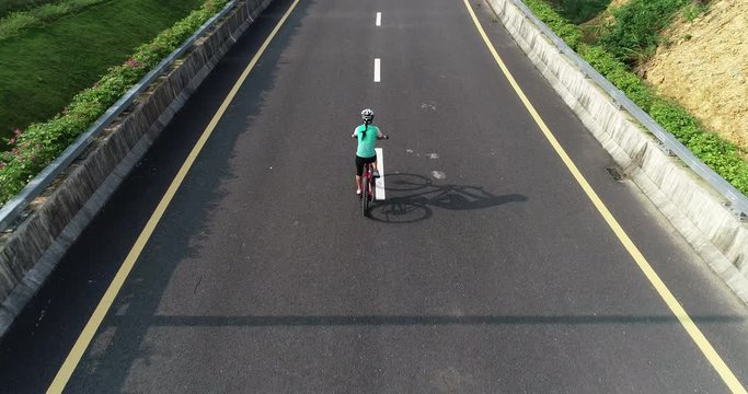 Aerial view of woman cyclist riding bike on highway road 