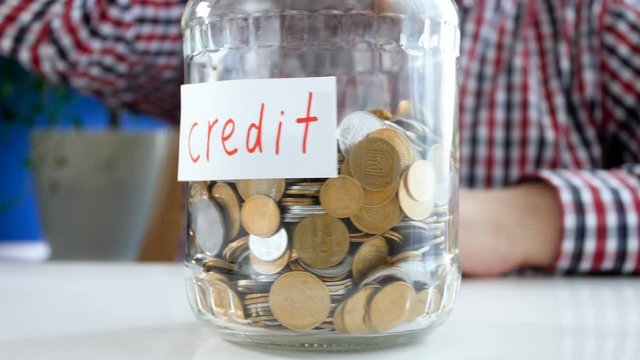 4k video of young money thowing money in glass jar labeled Credit
