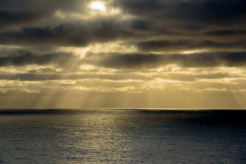 Sun shining through clouds over sea