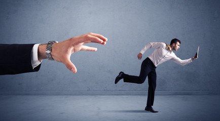 Young miniature businessman running from a big hand with blueish background