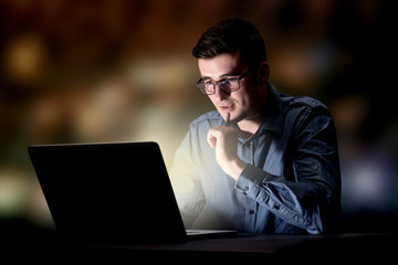 Young handsome businessman working late at night in the office
