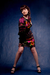 Beautiful brunette in color dress posing in studio.