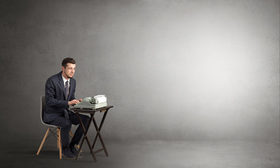 Man working hard on a typewriter in an empty space
