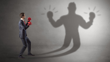 Businessman trying to fight with his unarmed shadow
