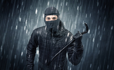 Naklejka premium Burglar in action in black clothes with rainy concept. 